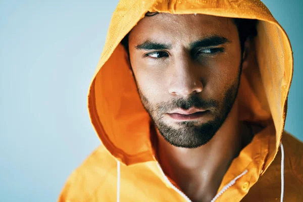 Lukk opp portrettet av en ung, kjekk mann i lys oransje regnfrakk – stockfoto