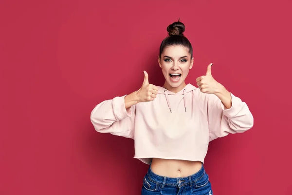 Feliz sorrindo hipster mulher mostrando polegares para cima no fundo rosa — Fotografia de Stock