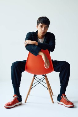 Stüdyoda poz verip kameraya bakan şık bir genç.