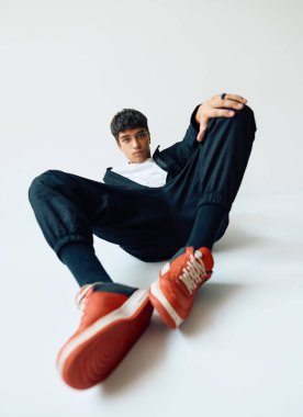 Young trendy mixed race man posing in studio lying on floor on white background