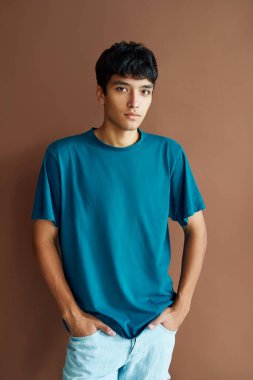 Stüdyo arka planında poz veren yakışıklı melez adam kameraya bakıyor.