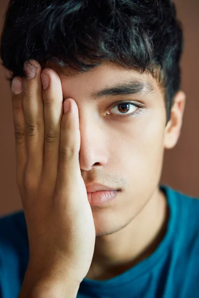Close up retrato de homem jovem cobrindo metade do rosto com uma mão e olhando por um olho — Fotografia de Stock