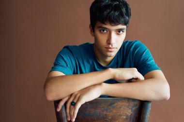 Stüdyoda poz verip kameraya bakan şık bir genç.