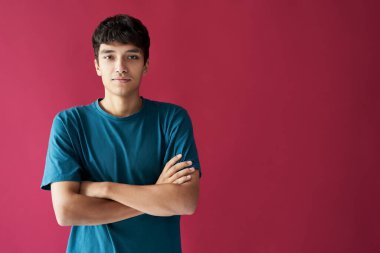 Pembe arka planda poz veren çapraz kollu trend karışık ırk adamı.