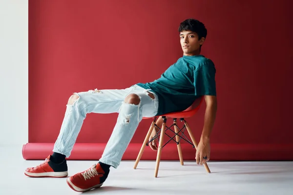 Elegante bonito jovem relaxe e posando no estúdio sentado em uma cadeira olhando para a câmera. — Fotografia de Stock