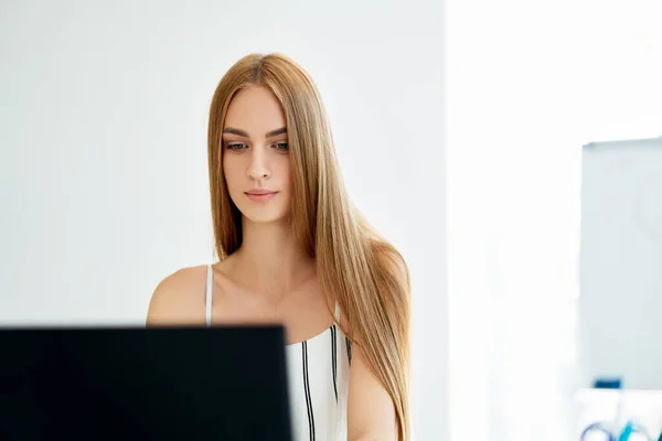 Jolie jeune femme d'affaires travaillant sur ordinateur portable dans un bureau moderne. — Photo