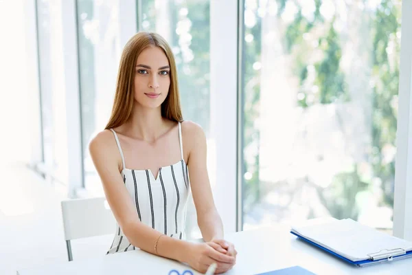 Bonita mujer de negocios posando en una oficina moderna sentada en su escritorio —  Fotos de Stock