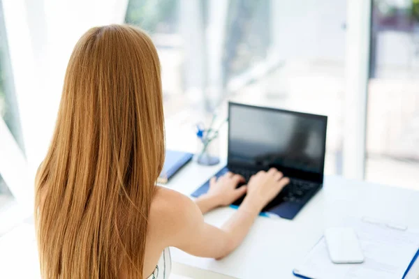 Visão traseira da jovem mulher de negócios que trabalha com laptop no escritório moderno — Fotografia de Stock