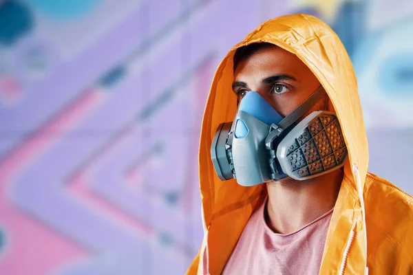 Γκράφιτι ζωγράφος με μάσκα αναπνοής στέκεται κοντά στον τοίχο με τους πίνακές του — Φωτογραφία Αρχείου