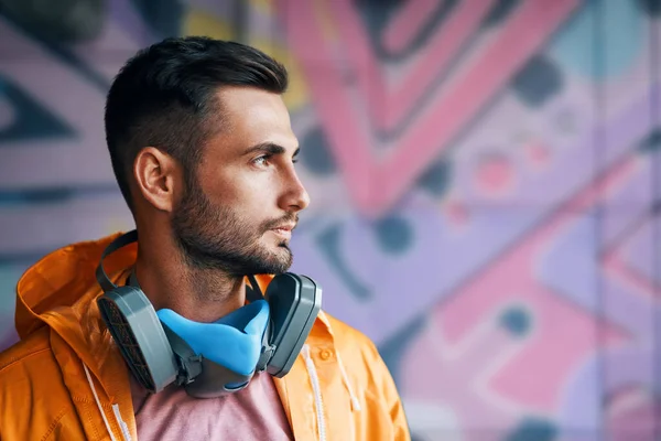 Portrait of handsome street artist staying on his graffiti painting background — Stock Photo, Image