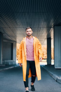 Modaya uygun bir genç adam caddede yürüyor ve kameraya bakıyor.