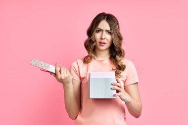 Pembe arka plandaki hediye kutusuyla hayal kırıklığına uğramış genç bir kadın.