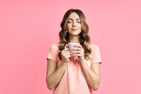 Young pretty woman enjoying cup of aroma coffee closed eyes on pink background — Stock Photo, Image