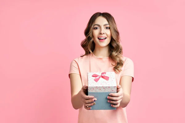 Pretty happy woman holding gift box on pink background — Stock Photo, Image