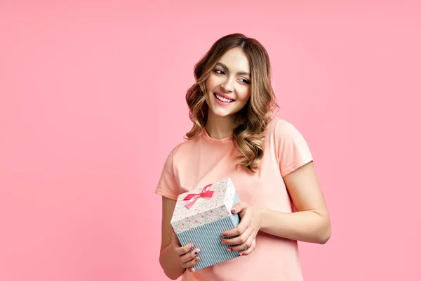 Pretty happy woman holding gift box on pink background — Stock Photo, Image