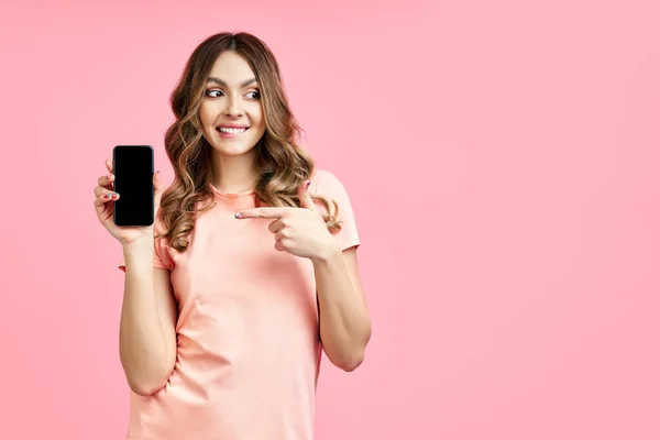 Mujer emocionada apuntando con el dedo al teléfono móvil y buscando copiar espacio — Foto de Stock