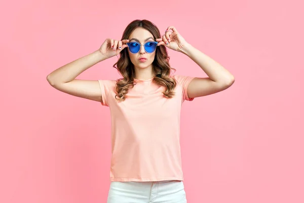 Mujer joven con estilo en gafas de sol azules sonriendo y posando en rosa —  Fotos de Stock