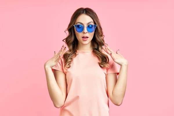 Κομψό έκπληξη γυναίκα σε μπλε γυαλιά ηλίου ποζάρουν σε ροζ φόντο — Φωτογραφία Αρχείου