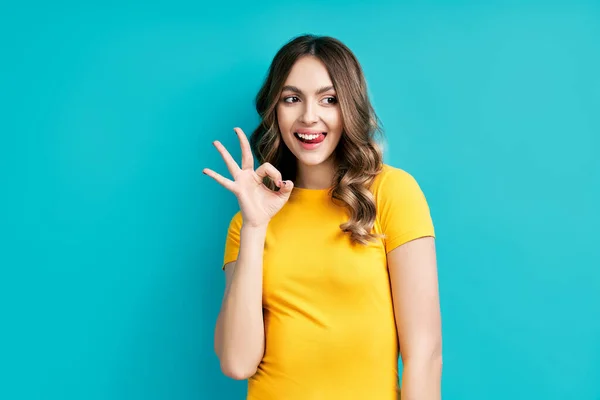 Mujer bastante sonriente mostrando signo OK con los dedos y la lengua hacia fuera —  Fotos de Stock