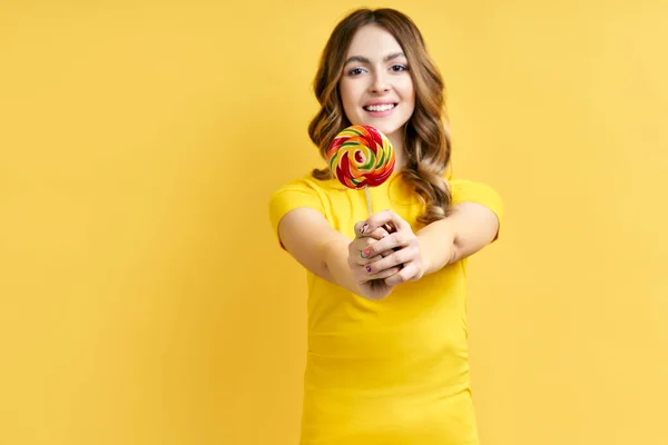Gelukkig mooi vrouw met kleurrijke lolly op geel — Stockfoto