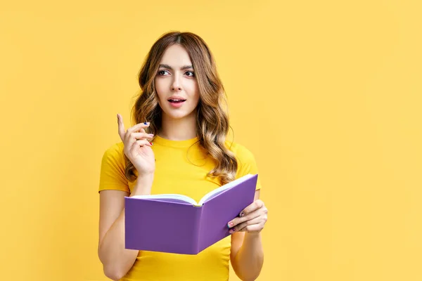 Sonhador positivo menina resto com livro no fundo amarelo com espaço de cópia — Fotografia de Stock