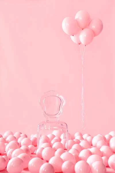 Leere transparente Stuhl auf rosa Pastell Hintergrund zwischen rosa Luftballons — Stockfoto