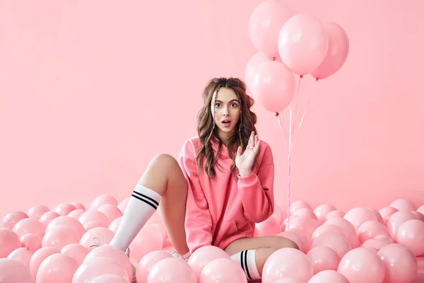 Jovem na moda mulher surpreso com balões rosa no fundo pastel rosa — Fotografia de Stock