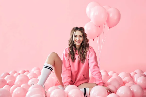 Young trendy woman posing with pink balloons on pink background — Stock Photo, Image
