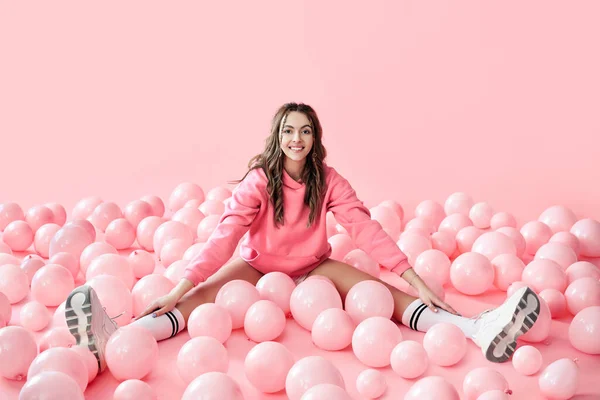 Ung trendig kvinna poserar med rosa ballonger på rosa bakgrund — Stockfoto
