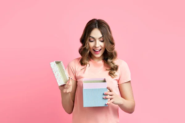 Mulher sorridente animado abrir caixa de presente sobre fundo rosa — Fotografia de Stock