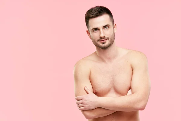 Retrato de hombre musculoso guapo confiado con los brazos cruzados y el torso desnudo mirando en la cámara sobre fondo rosa — Foto de Stock