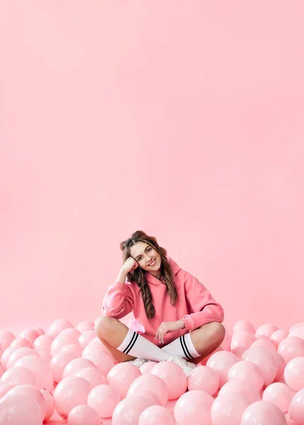 Модний портрет молодої чарівної усміхненої жінки, яка позує з рожевими кульками на рожевому фоні — стокове фото