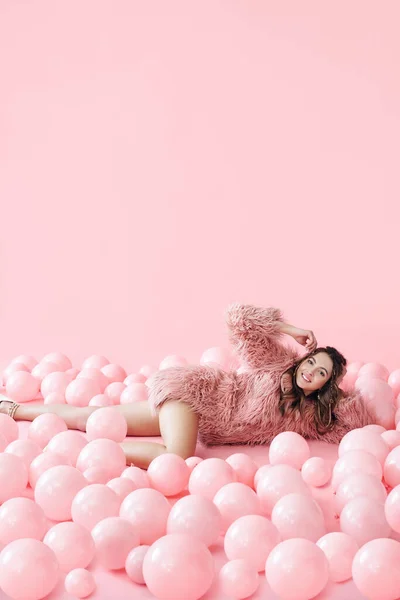 Retrato de moda de mujer bonita sonriente acostada en muchos globos rosados sobre fondo pastel rosado —  Fotos de Stock