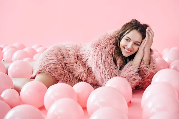 Μόδα πορτρέτο του χαμογελαστού όμορφη γυναίκα που βρίσκεται σε πολλά ροζ μπαλόνια — Φωτογραφία Αρχείου