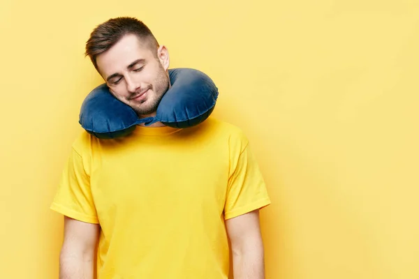 Jovem com olhos fechados descansando em travesseiro de viagem sobre fundo amarelo — Fotografia de Stock