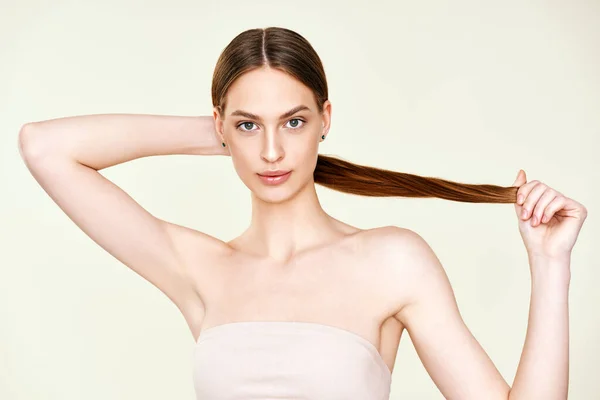 Närbild porträtt av vackra unga kvinna med naturlig make up poserar på studio bakgrund. — Stockfoto