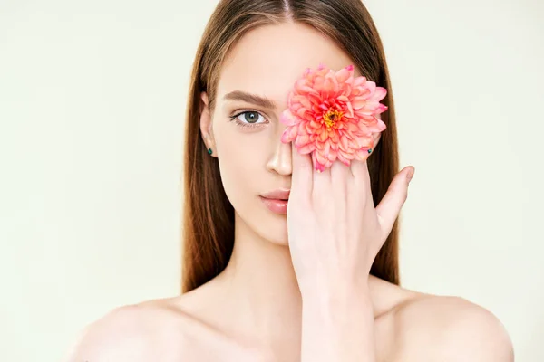Zbliżenie portret pięknej młodej kobiety zakrywającej jej oko kwiatem — Zdjęcie stockowe