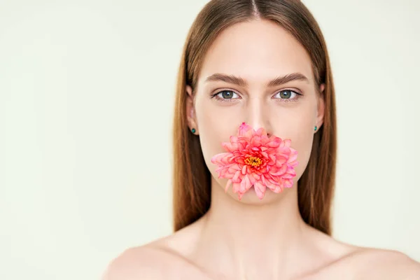 Piękna młoda kobieta trzyma kwiat w ustach. — Zdjęcie stockowe