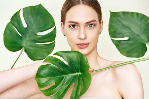 Gros plan portrait de jeune belle femme avec une peau lisse parfaite en feuilles tropicales — Photo