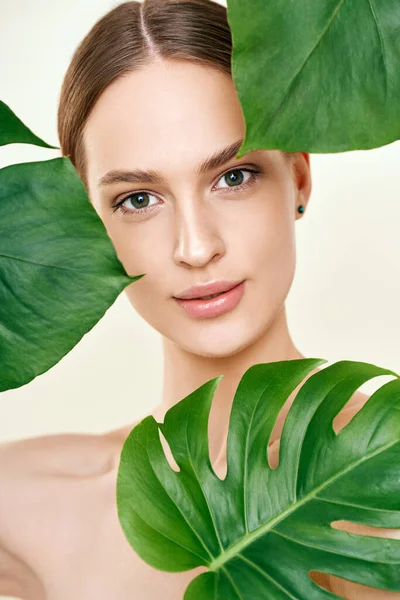 Close up portrait of young beautiful woman with perfect smooth skin in tropical leave — Stok fotoğraf