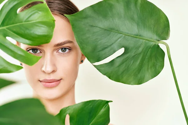 Close up portrait of young beautiful woman with perfect smooth skin in tropical leaves — Stok fotoğraf