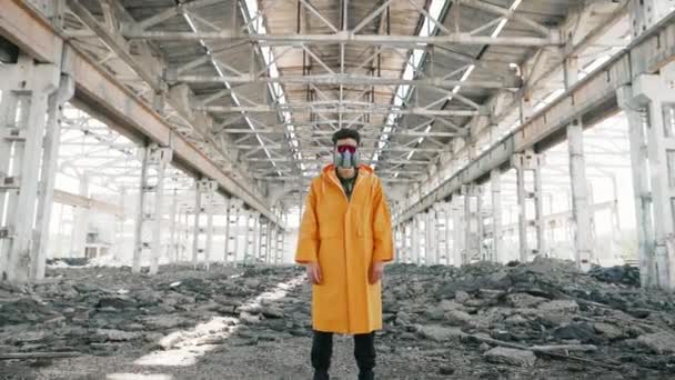 Joven con máscara protectora permaneciendo en un edificio abandonado en ruinas — Vídeo de stock