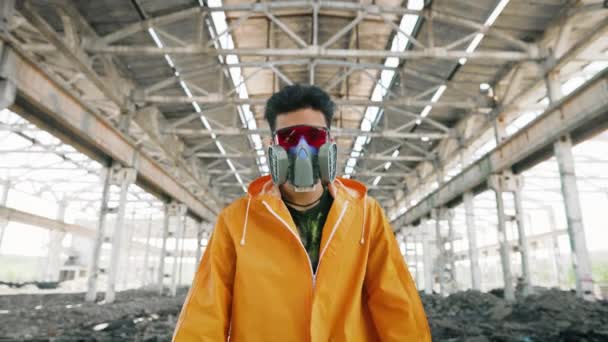 Un joven con máscara protectora va a la cámara en un edificio abandonado en ruinas — Vídeo de stock