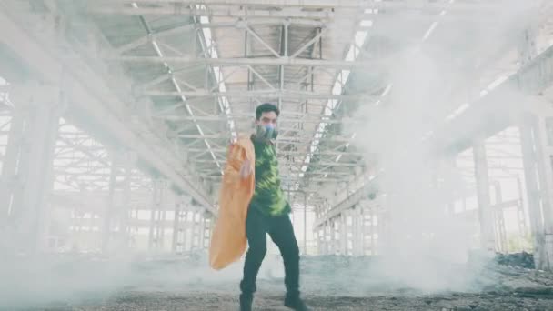 Jonge mannelijke danser in beschermende masker dansen in geruïneerd verlaten gebouw in gekleurde rook — Stockvideo