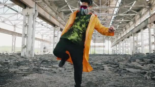 Nuori miestanssija suojelevassa naamiossa tanssii raunioituneessa hylätyssä rakennuksessa — kuvapankkivideo