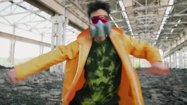 Mladý muž tanečník v ochranné masce tanec v zničené opuštěné budovyv s barevným kouřem na pozadí — Stock video