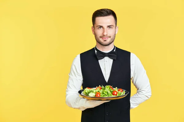 Счастливый улыбающийся официант держит тарелку со здоровым овощным салатом, готовым подавать — стоковое фото