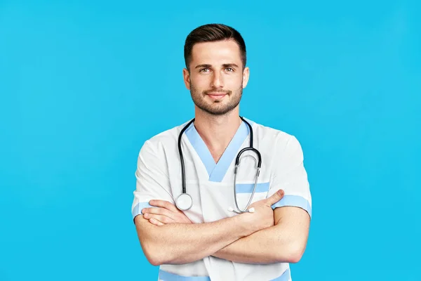 Portret van een zelfverzekerde lachende mannelijke arts met stethoscoop in medisch uniform over een blauwe achtergrond. — Stockfoto