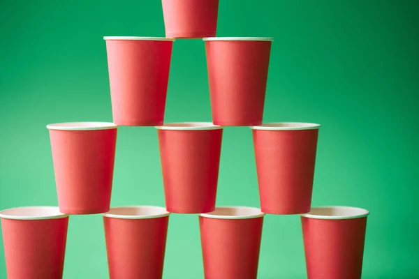 Pyramid of pink paper cups on green background. — Stock Photo, Image