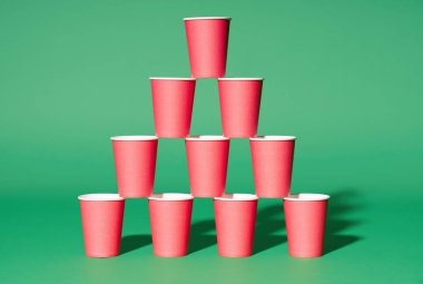 Yeşil zemin üzerinde kırmızı kağıt bardaklar piramidi